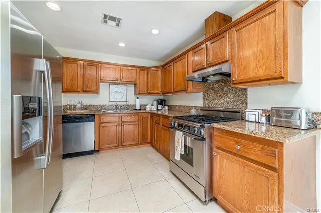 a kitchen with stainless steel appliances granite countertop a stove top oven a sink and dishwasher