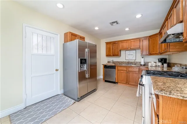 a kitchen with stainless steel appliances granite countertop a refrigerator and a sink