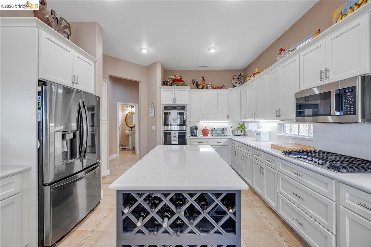 158 Rock Ridge Lane Copperopolis, CA 95228 - Photo 22 of 72 Spacious kitchen featuring an expansive center island with integrated wine storage, white cabinetry, stainless steel appliances, and a gas cooktop