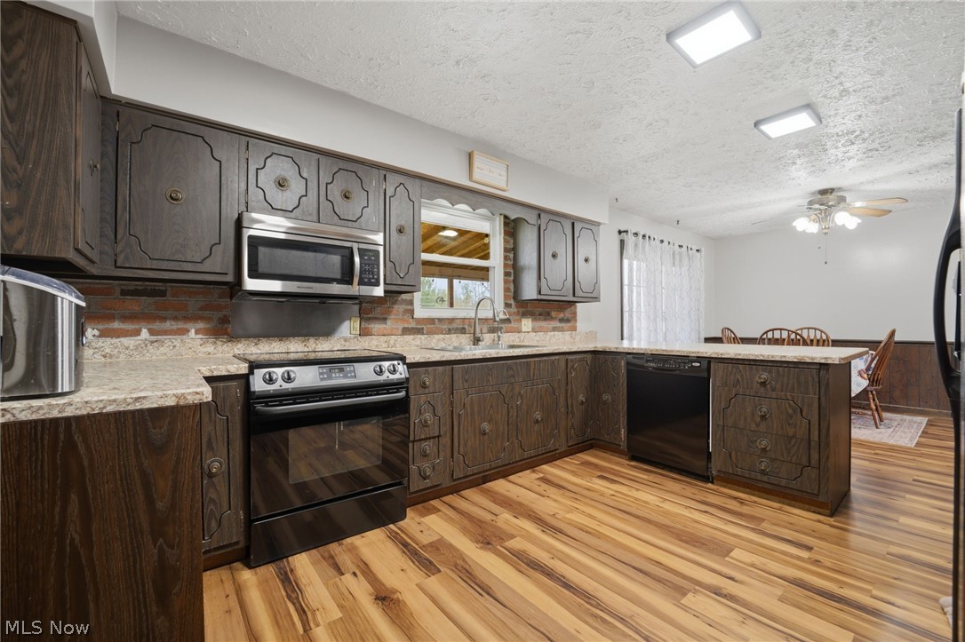 14557 Ellsworth Road Berlin Center, OH 44401 - Photo 7 of 23 Kitchen featuring a peninsula, black appliances, dark wood finish cabinets, ceiling fan, and a textured ceiling
