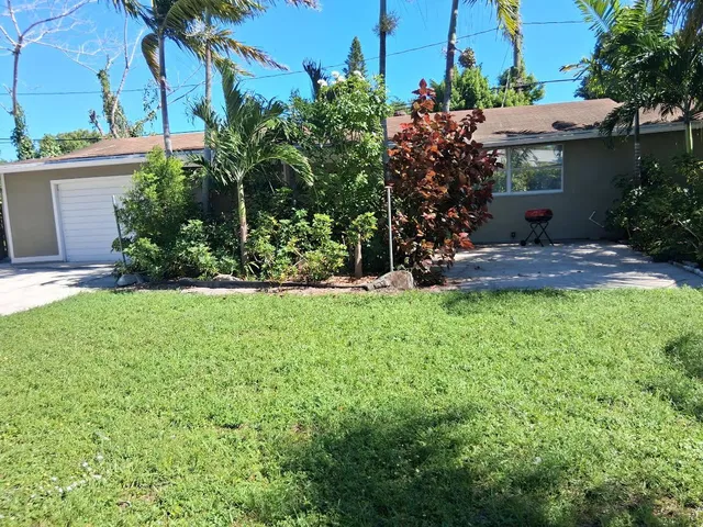 a view of a house with a yard and potted plants