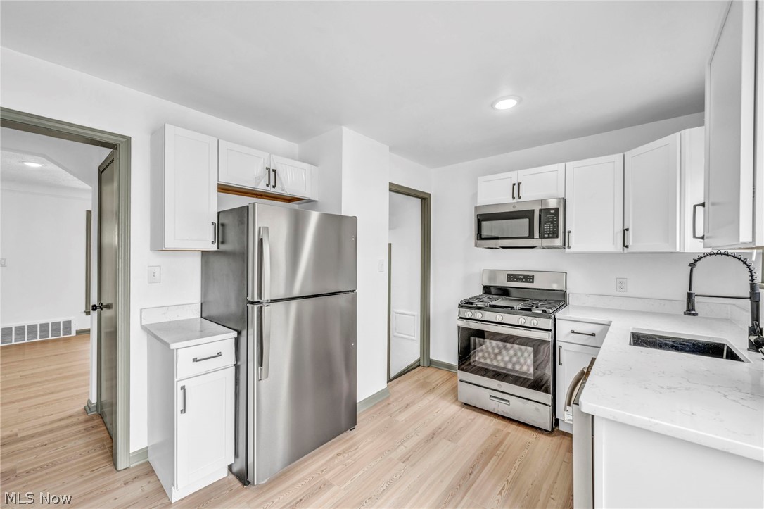 1609 Mapledale Road Wickliffe, OH 44092 - Photo 12 of 46 Kitchen with appliances with stainless steel finishes, light hardwood / wood-style flooring, sink, and white cabinetry