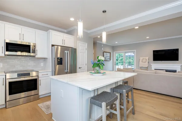 a kitchen with stainless steel appliances a stove a sink a microwave a refrigerator a stove and white cabinets