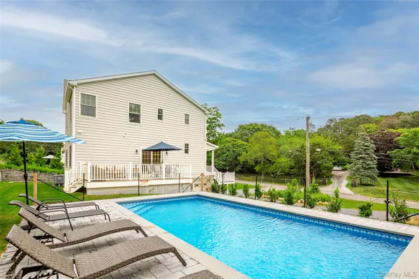 a view of a house with pool and chairs in patio