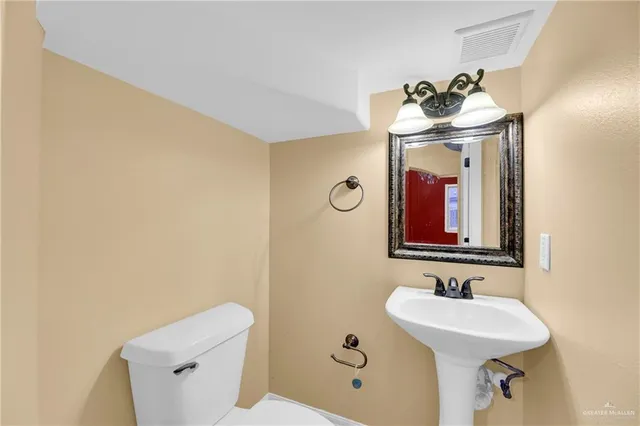 a bathroom with a sink and mirror with toilet