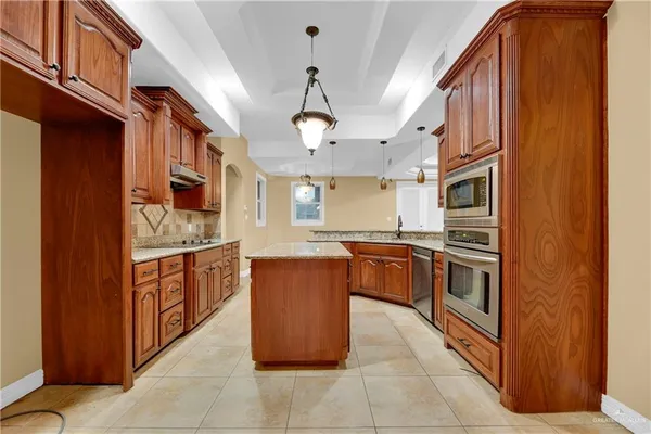 a large kitchen with stainless steel appliances granite countertop a stove and a refrigerator