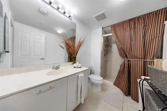 a bathroom with a sink a toilet a mirror and shower