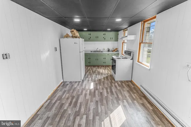 a kitchen with a refrigerator and white cabinets with wooden floor