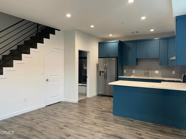 a view of kitchen with stainless steel appliances wooden floor and cabinets