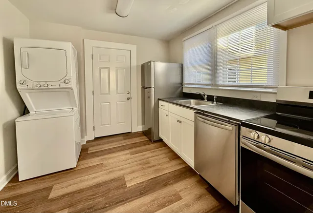 a kitchen with granite countertop a refrigerator a sink and wooden floors
