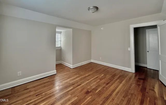 a view of an empty room with wooden floor and closet