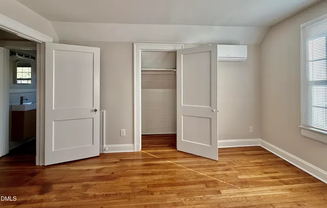 an empty room with wooden floor closet and windows