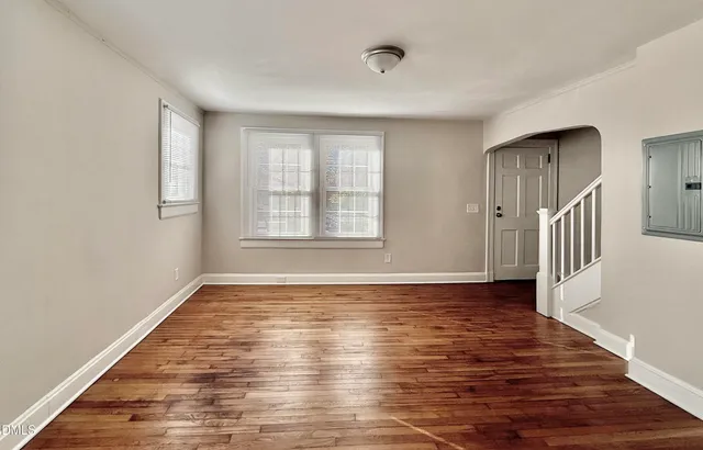 a view of an empty room with wooden floor and a window