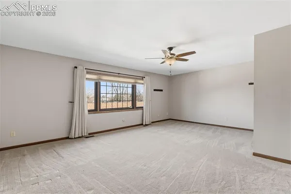 an empty room with chandelier fan and windows