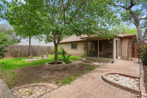a view of a backyard with wooden fence and a large tree