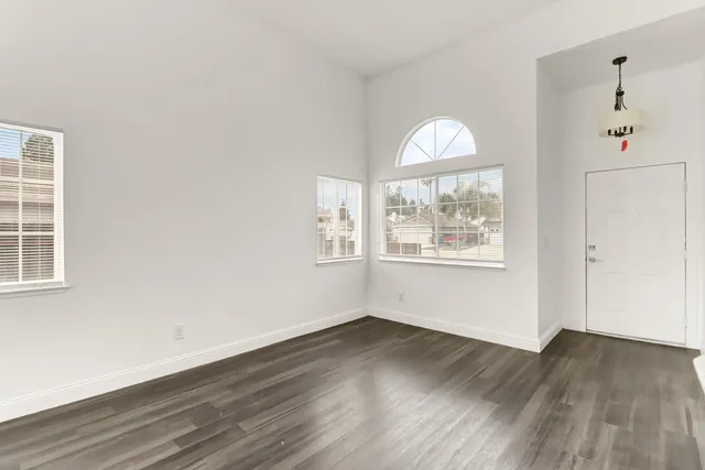 an empty room with wooden floor exposed radiator and windows