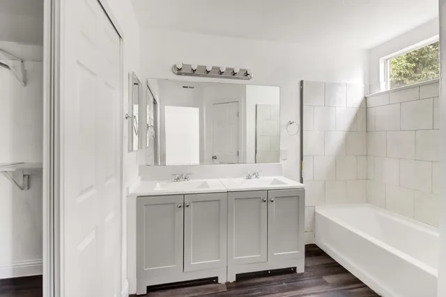 a bathroom with a tub sink and mirror