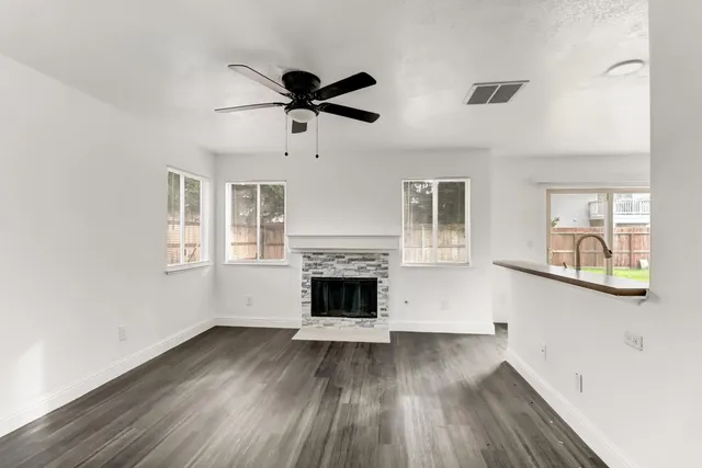 a view of a livingroom with wooden floor a fireplace and windows