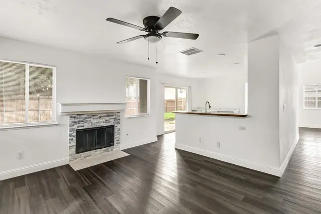 an empty room with wooden floor a fireplace and windows