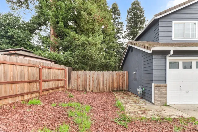 a view of a backyard with wooden fence and large trees