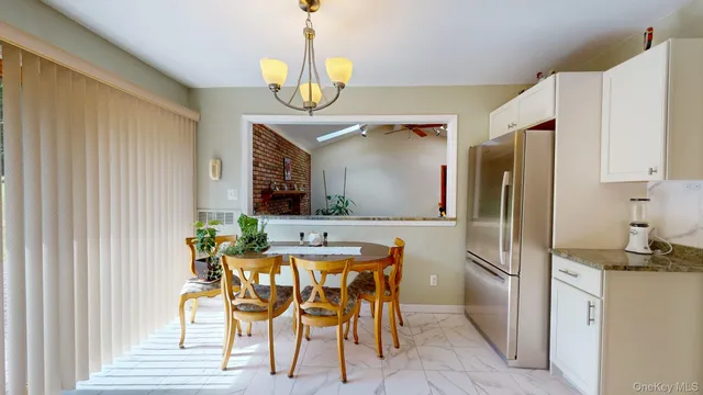 a kitchen with stainless steel appliances kitchen island granite countertop a refrigerator a stove a microwave oven a dining table and chairs with wooden floor