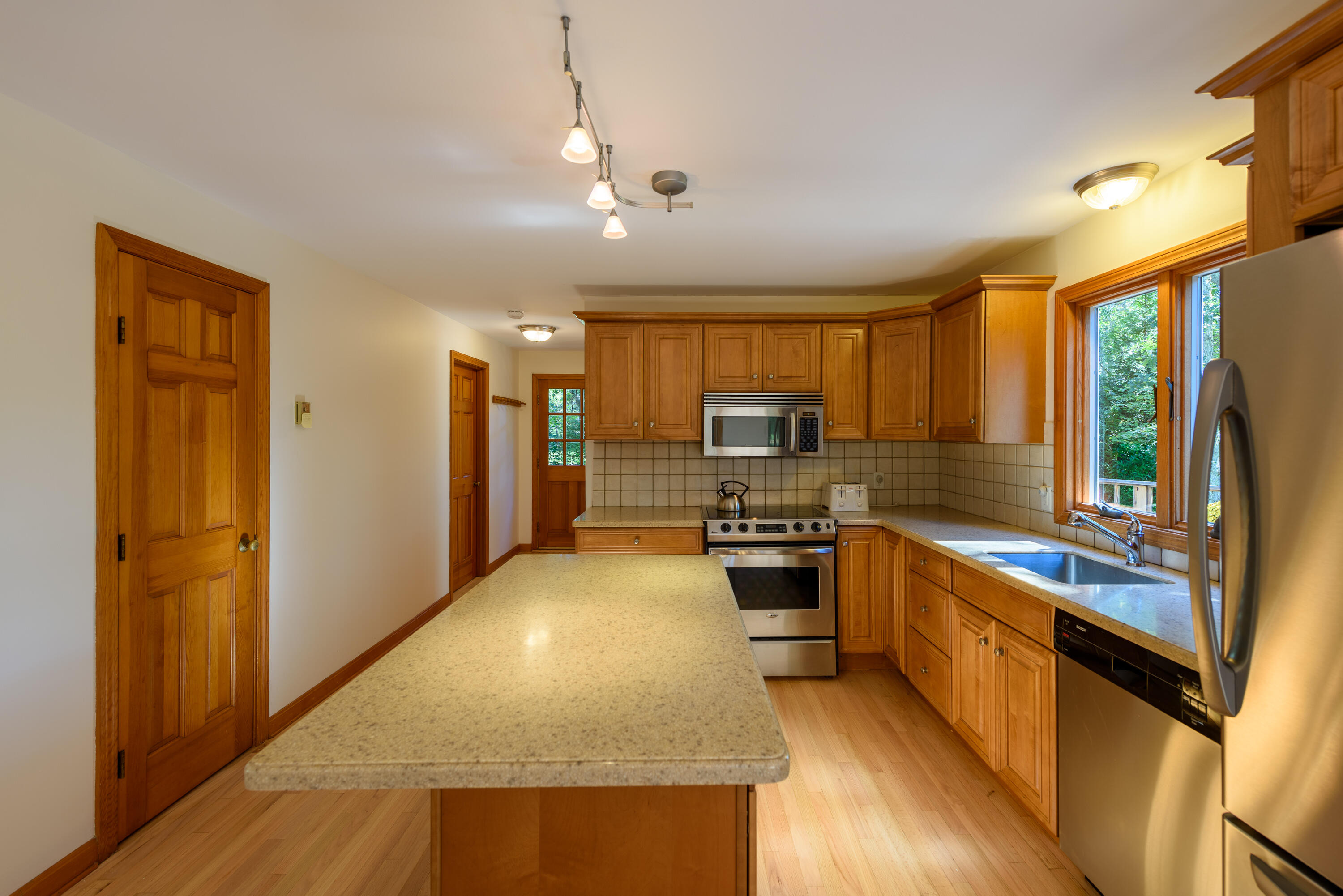 44 Marthas Road Edgartown, MA 02539 - Photo 21 of 30 a large kitchen with kitchen island granite countertop a refrigerator a stove top oven a sink with wooden floor and cabinets