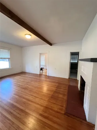 an empty room with wooden floor and fireplace