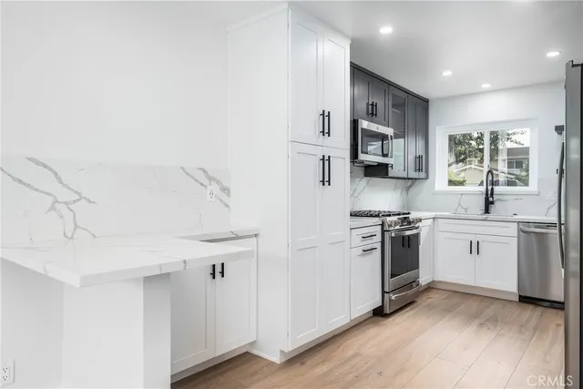 a kitchen with stainless steel appliances a sink cabinets and a window