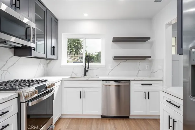 a kitchen with stainless steel appliances white cabinets and a stove top oven