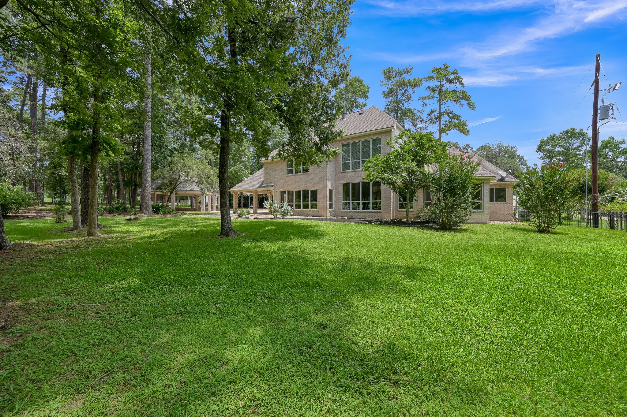 2205 Longmire Road Conroe, TX 77304 - Photo 39 of 49 Two-story brick house surrounded by lush greenery and mature trees, providing a serene and private setting.