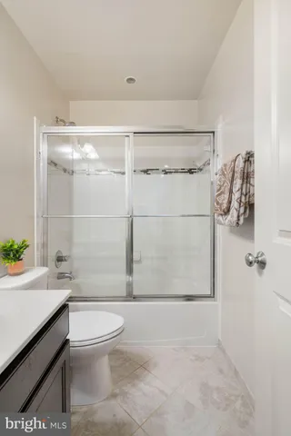 a bathroom with a granite countertop bathtub shower sink vanity and toilet