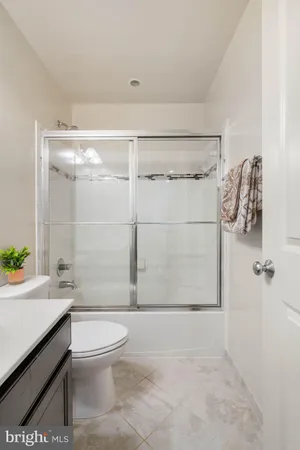 a bathroom with a granite countertop bathtub shower sink vanity and toilet