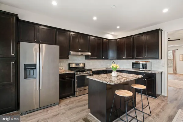 a kitchen with a refrigerator a stove a sink and a microwave with wooden floor