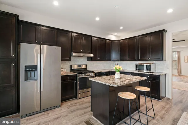 a kitchen with a refrigerator a stove a sink and a microwave with wooden floor