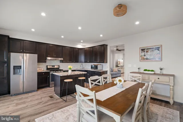 a kitchen with a refrigerator a stove top oven a sink dishwasher and white cabinets with wooden floor