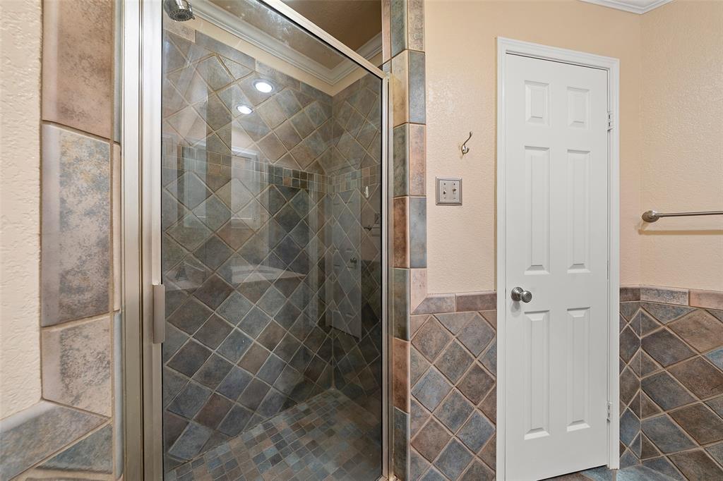 712 North Old Robinson Road Robinson, TX 76706 - Photo 15 of 26 Full bathroom featuring a stall shower, tile walls, crown molding, and a wainscoted wall
