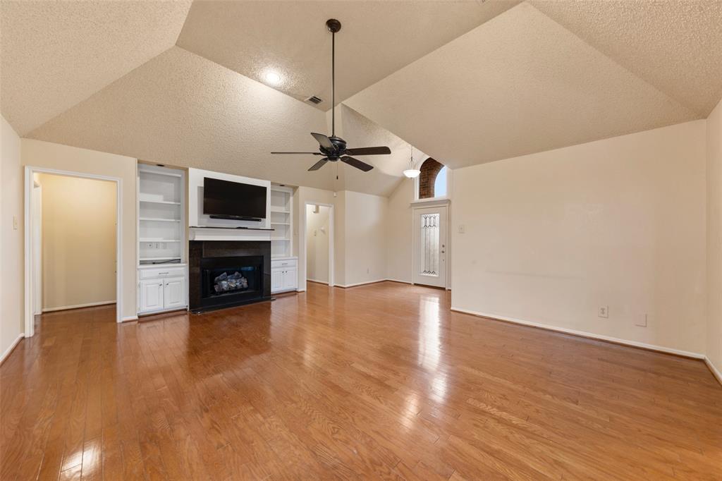 712 North Old Robinson Road Robinson, TX 76706 - Photo 2 of 26 Unfurnished living room with vaulted ceiling, a textured ceiling, built in shelves, a fireplace, and light wood finished floors