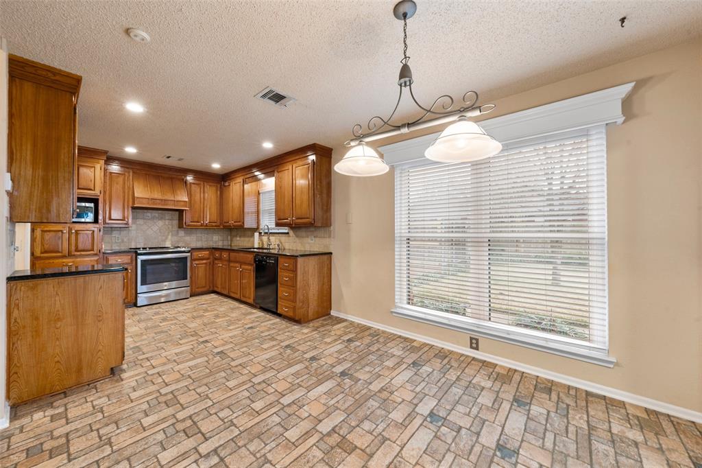 712 North Old Robinson Road Robinson, TX 76706 - Photo 4 of 26 Kitchen with brown cabinetry, stainless steel range oven, pendant lighting, a textured ceiling, and black dishwasher