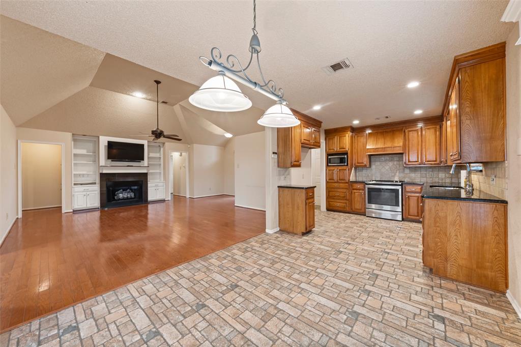 712 North Old Robinson Road Robinson, TX 76706 - Photo 26 of 26 Kitchen featuring brown cabinetry, built in features, open floor plan, decorative light fixtures, and a fireplace