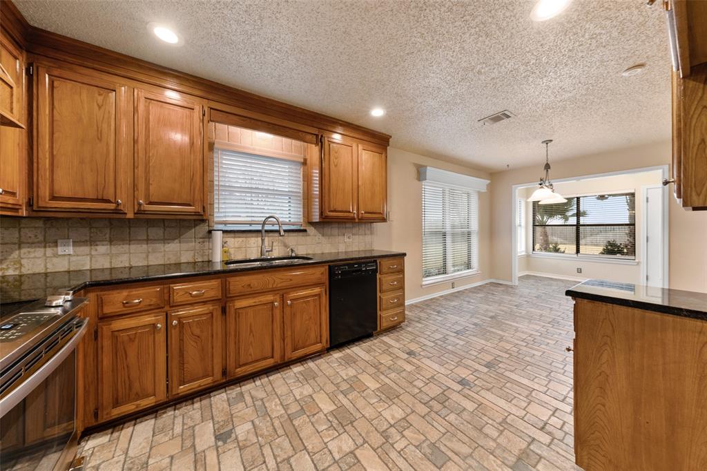 712 North Old Robinson Road Robinson, TX 76706 - Photo 7 of 26 Kitchen featuring brown cabinetry, stainless steel range with electric cooktop, pendant lighting, dark stone counters, and black dishwasher