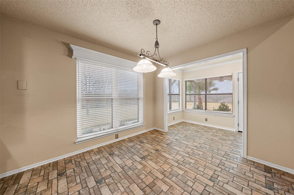 712 North Old Robinson Road Robinson, TX 76706 - Photo 8 of 26 Empty room with a textured ceiling, healthy amount of natural light, and brick patterned floors