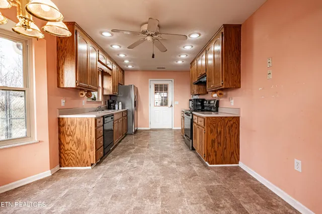 a large kitchen with granite countertop a stove a sink a window and dining table