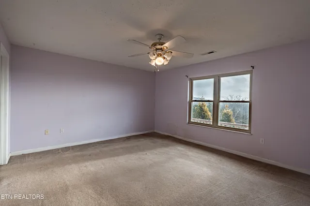 an empty room with windows and fan