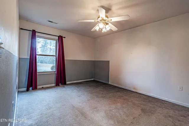 an empty room with windows and fan