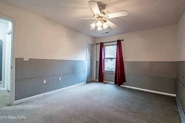 an empty room with windows and chandelier fan