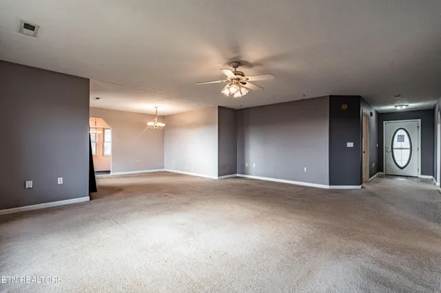 a view of an empty room with a chandelier fan