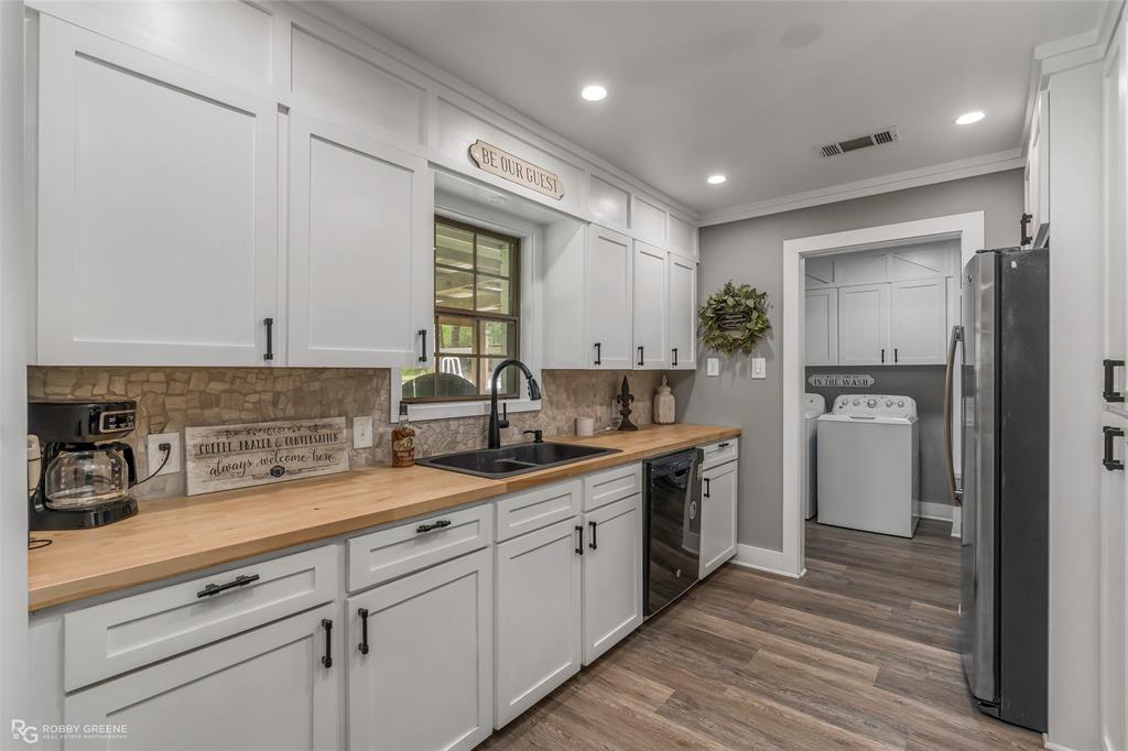 1426 Caney Lake Road Minden, LA 71055 - Photo 10 of 36 White shaker cabinetry with matte black hardware, wood-finish countertops, stone tile backsplash, and a black double basin sink with a gooseneck faucet