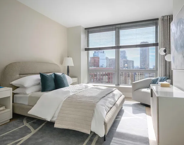 a bedroom with a bed lamp and a large window