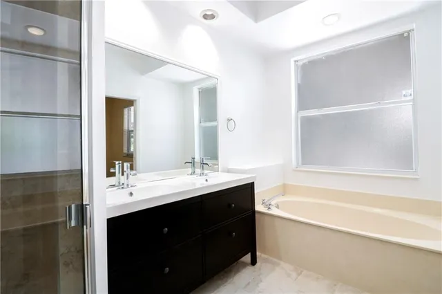a bathroom with a tub sink double vanity and mirror