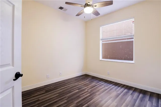 a view of a room with wooden floor and a ceiling fan